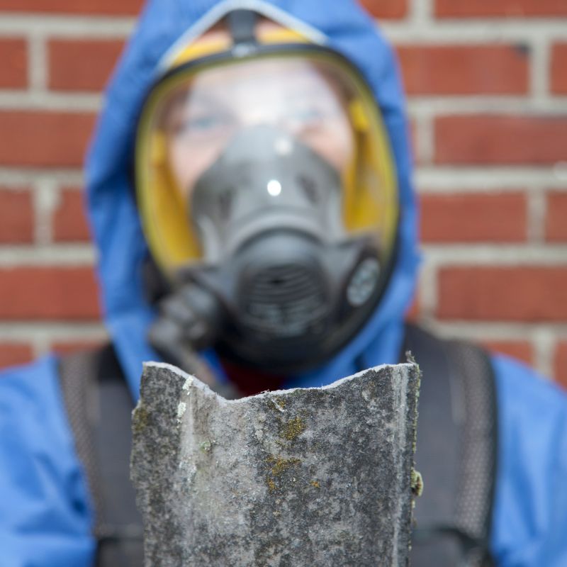 A man wearing a gas mask grips a large rock, symbolizing mold removal efforts in Irvine, CA.